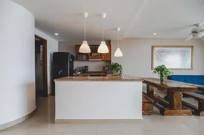 a kitchen with a white island and a wooden table at SkyMar Luxury 27 in Cartagena de Indias