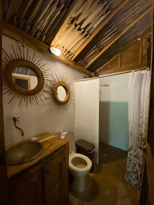a bathroom with a toilet and a sink and mirrors at Cabañas roble verde in Rincón