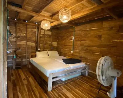 a bed in a wooden room with a fan at Cabañas roble verde in Rincón