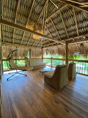 a living room with chairs and a couch in a straw hut at Cabañas roble verde in Rincón
