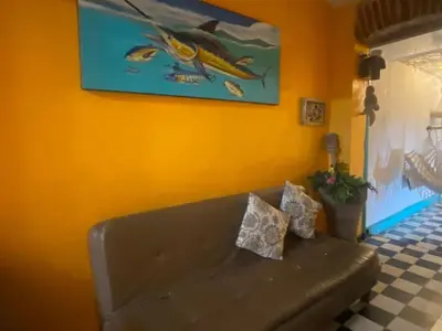 a couch in a living room with a fish painting on the wall at 4CR-1M CASA DE 4 HABITACIONES EN EL CENTRO HISTORICO, GETSEMANI in Cartagena de Indias