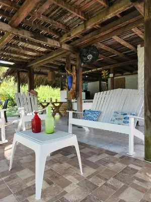 a patio with white chairs and a table and a bench at Cabana Ferrer in Notecebes
