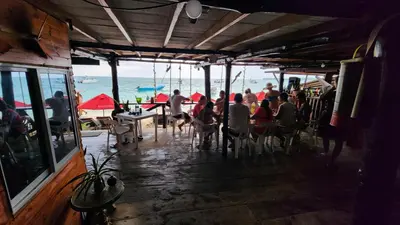 a group of people sitting at a restaurant on the beach at Ecohotelhector in Playa Blanca