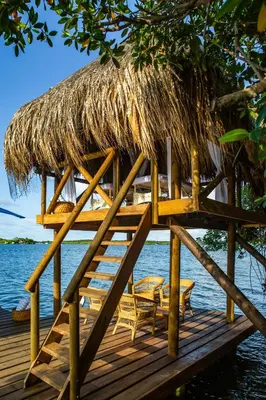 a wooden deck with chairs and a thatch roof at Hotel Agua Baru by Mustique in Baru
