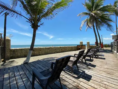 a row of chairs on a boardwalk with the beach at Apto 1er piso frente a la playa y con piscina in San Bernardo del Viento