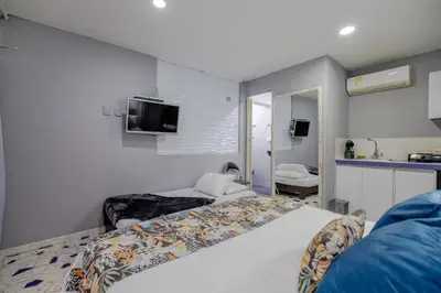 a bedroom with two beds and a tv on the wall at Mini departamento a una cuadra de la playa y de la bahia de Bocagrande in Cartagena de Indias
